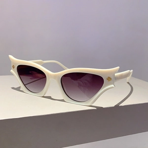 Détail de lunettes œil de chat blanches irrégulières avec verres violets et logos dorés