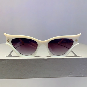 Détail de lunettes de soleil œil-de-chat blanches avec décorations poissons dorées et verres