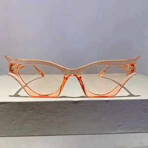 Détail de lunettes œil de chat orange avec charnières dorées sur surface texturée