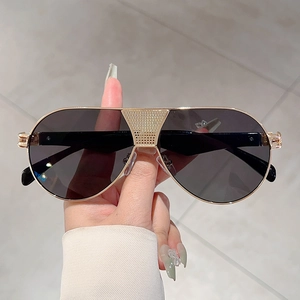 Detail of the golden aviator frame showing the micro-grid textured bridge and dark lenses