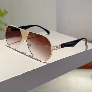 Detail of aviator sunglasses showing gold metal frame with textured bridge and gradient lenses