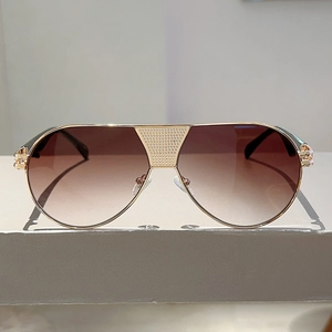 Detail of pilot sunglasses with gold metal frame and gradient brown lenses on stone