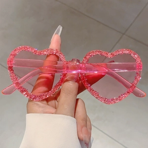 Close-up of pink heart-shaped rimless sunglasses with sparkling glitter and rhinestones