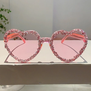 Close-up of pink heart-shaped frameless sunglasses with sparkling rhinestone trim
