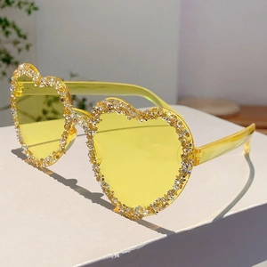 Close-up of heart-shaped rimless yellow sunglasses with sparkling inlaid rhinestones