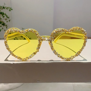 Close-up of heart-shaped sunglasses with yellow lenses and sparkling crystal rim