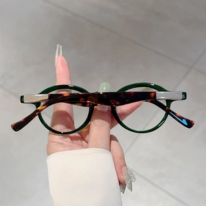 Close-up of retro round green glasses frames with tortoise shell temples in hand