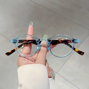 Retro round glasses with transparent blue and tortoise shell layered frame held by hand