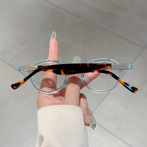 Detail of round light blue glasses frames with tortoise shell patterned temples and hinges