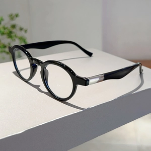 Detail of retro black round frame glasses with silver metal hinges on a display stand