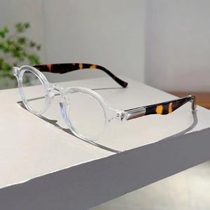 Detail of round transparent glasses with tortoiseshell temples and metal hinges