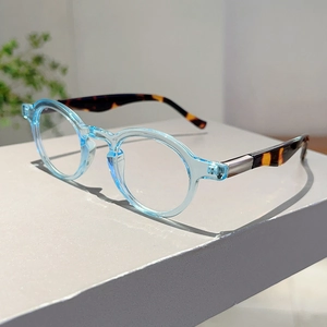 Detail of round light blue glasses with tortoiseshell temples and metal accents