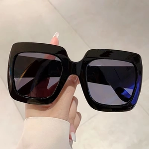 Detail of square oversized black sunglasses with thick frames and dark lenses