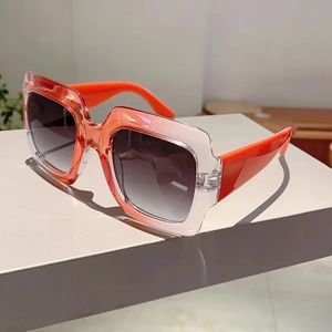 Detail view of square oversized sunglasses with orange gradient frames and grey lenses