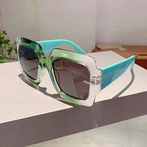 Detail of square oversized sunglasses with gradient green frame and teal temples