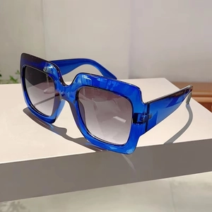 Detail view of bold square blue resin sunglasses with grey gradient lenses on a pedestal