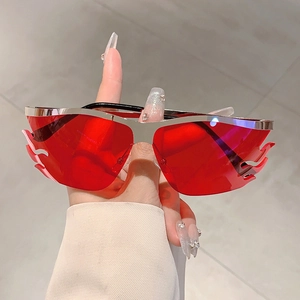 Detailed view of flame shaped rimless sunglasses with red lenses and silver metal frame
