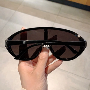 Detail of trendy Y2K oversized sunglasses with glossy black frame and one-piece dark lens