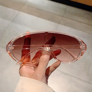 Detail view of pink transparent oversized wrap sunglasses with brown gradient lenses