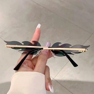 Detail of rimless fire flame sunglasses with gold metal frame and dark grey lenses