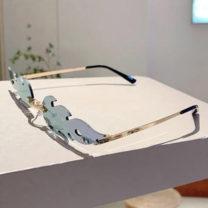 Detail of light blue flame-shaped rimless sunglasses with gold metal temples on a white stand