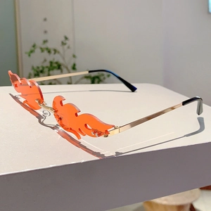Detailed view of frameless flame-shaped sunglasses with orange lenses and golden metal frame