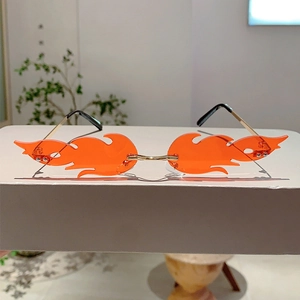 Detail of frameless fire-shaped sunglasses with orange gradient lenses and gold metal frame