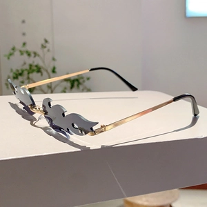 Detail of rimless flame-shaped sunglasses with dark grey lenses and gold metal temples
