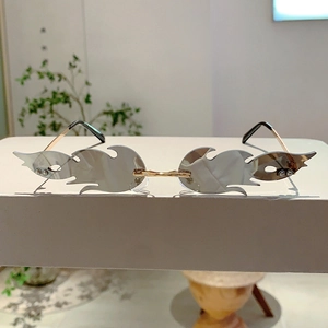 Close-up of silver flame-shaped rimless sunglasses with wave textures and metal temples