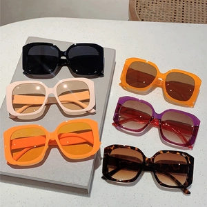 Modern square frame sunglasses in multiple colors shown on a textured display surface