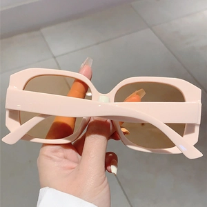 Detail view of pink square frame sunglasses with light tea lenses and smooth texture