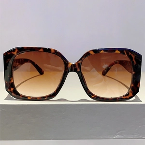 Detail of square oversized tortoiseshell sunglasses with brown gradient lenses on a pedestal