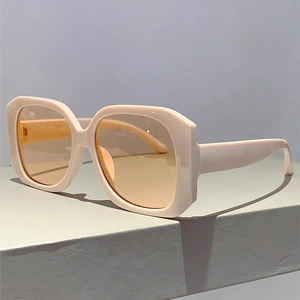 Detail view of square off-white frame sunglasses with light orange lenses on grey base