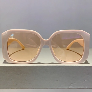 Close-up of stylish square frame sunglasses with nude pink acetate and tinted lenses