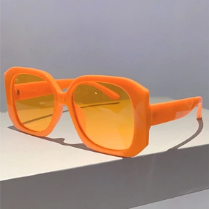 Close-up of square orange sunglasses with yellow lenses on a display stand