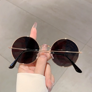 Detail of round gold metal frame sunglasses with dark lenses and retro fashion design