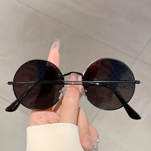 Close-up of retro round sunglasses with black tinted lenses and slim black metal frame