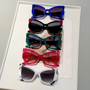 Collection of five colorful cat-eye sunglasses with gradient lenses on a white display tray