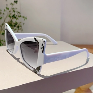 Detail of white cat eye sunglasses with marble pattern accents and grey gradient lenses