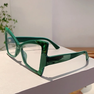 Close-up of green cat-eye glasses with marble pattern on a minimalist white stand