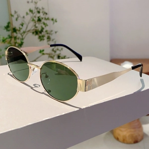 Close-up of vintage oval sunglasses with gold metal frame and dark green lenses
