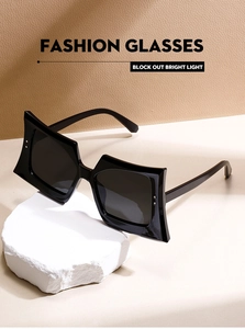 Close-up of oversized geometric butterfly sunglasses on white stone with metallic rivets