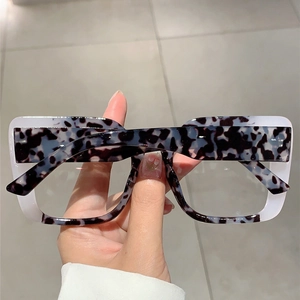 Detail of square oversized glasses frame with inner tortoiseshell and outer creamy white layer