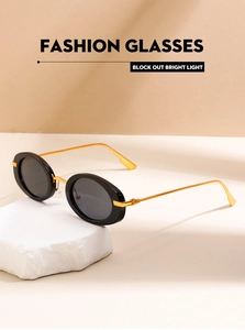 Detail of retro oval sunglasses with black frames and gold metal temples on stone