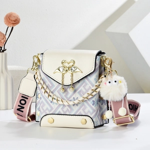Detail of crossbody bag with golden swan ornament, pearl pendant, and plush monster charm
