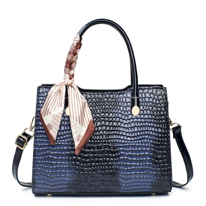 Detail of navy blue croc-embossed tote bag with decorative silk scarf and gold hardware