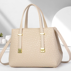 Detail of cream white handbag featuring dense woven texture and gold metal hardware