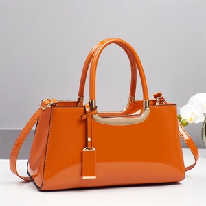 Glossy bright orange patent leather handbag with gold metal hardware and top handles