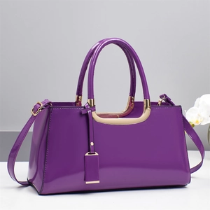 Detail of glossy purple patent leather handbag with gold-tone hardware and orchid decor