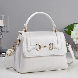 Close-up of white embossed leather handbag with gold horsebit buckle and top handle